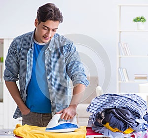 Young man husband doing clothing ironing at home