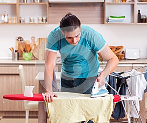 Young man husband doing clothing ironing at home