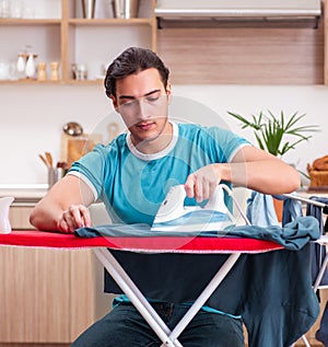 Young man husband doing clothing ironing at home