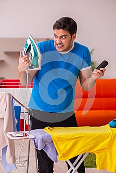 Young man husband doing ironing at home