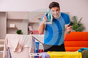 Young man husband doing ironing at home