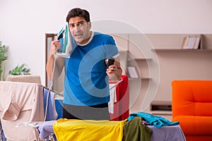 Young man husband doing ironing at home