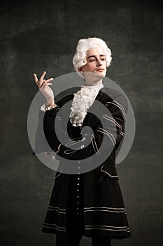 Young man in image of Amadeus Mozart, medieval person  on dark green vintage background. Retro style, comparison