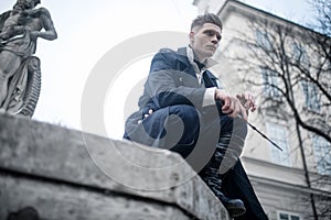 Young man in image of black magician with magic wand on street