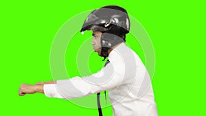 Young man imitating as riding motorcycle against green background