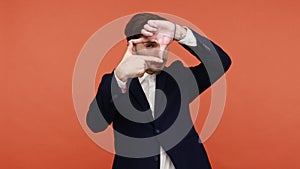 Young man imitating zoom focus, frame shape with fingers