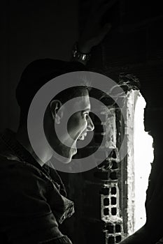 Young man indoor screaming out through hole in the wall