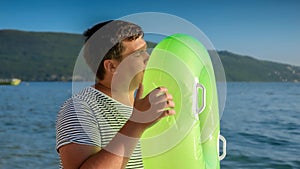 Young man with an inflatable swimming ring on a tranquil beach at sunset. Tourism, the joy of summertime, oceanic