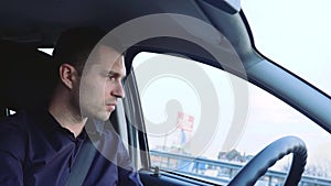 Young man inside car. Driver sitting in front seat and riding alone. Concentrated and serious businessman driving