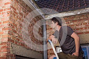 Young man inspecting the wall of an old house