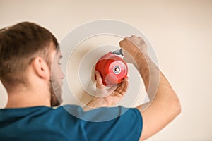 Young man installing alarm bell on wall