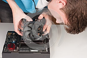 Young man installing CPU cooler fan on gaming motherboard