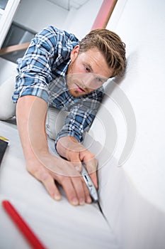 Young man installing flooring fitting next piece