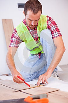 Young man installing laminate flooring in new apartment