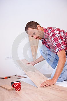 Young man installing laminate flooring in new apartment or house. Home improvement and renovation concept