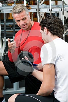 Young man with instructor at gym