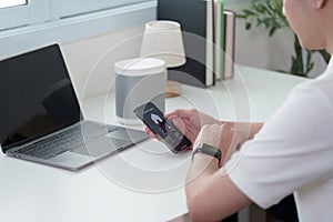 Smart Technology. A man using smartphone with smart speaker on desk.