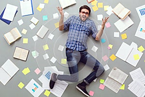 Young man isolated on grey background with papers and notes unsatisfied