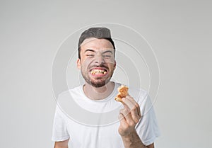 Young man isolated over background. Cheerful happy but strange guy smiling wide and showing teeth with burger pieces