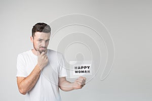 Young man isolated over background. Dissapointed scary guy hold piece of paper in hand and look on camera. Thoughtful photo