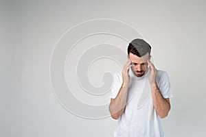 Young man isolated over background. Headache or thinking. Calm peaceful guy in studio stand alone and look down.