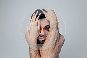 Young man isolated over background. Portrait of a worried guy covering face with hands. Madness and disorder. Worried