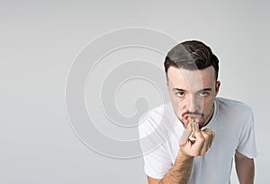 Young man isolated over background. Strange weirdo look straight on camera and biting piece of yummy tasty burger. Guy