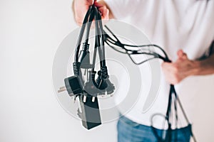 Young man isolated over white background. Cut view and close up of guy holding black cables and electrical cords in
