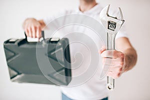 Young man isolated over white background. Cut view of guy holding box and wrench in hands. Repain man of fixing plumber.