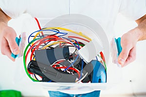 Young man isolated over white background. Cut view of man`s hands holding plastic box with cords and batteries