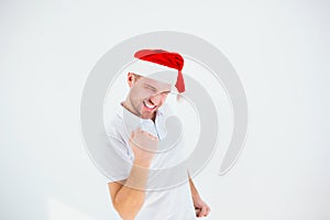 Young man isolated over white background. Guy cheering and in joyful mood. Alone in studio wearing santa hat. Christmas