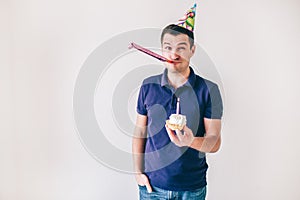 Young man isolated over white background. Guy hold small cake with candle on it celebrating birthday. Lonely on party