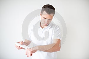 Young man isolated over white background. Guy moisturising his hands with cream. Body care concept. Wellness and beauty.