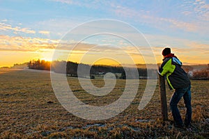 Young man in jacket looking to famous witer sunrise on Czech countryside