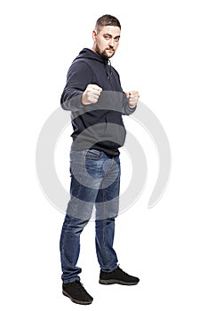 A young man in jeans in a fighting stance. Full height. Isolated over white background.