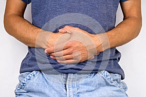 young man in jeans and t-shirt holds hands to his stomach