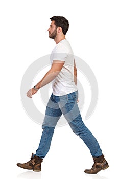 Young Man In Jeans And White T-shirt Is Walking Side View