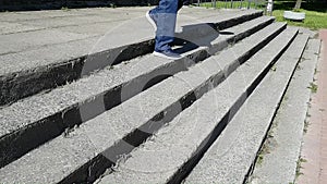 A young man in jeans and a windbreaker slowly descends the old city stairs. Man limps, he has cerebral palsy