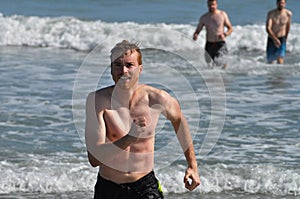 Young Man Jogging out of the Ocean After Swimming