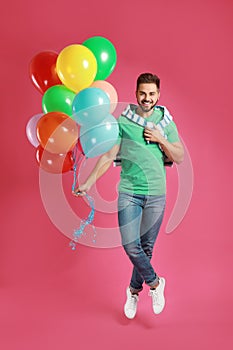 Young man jumping with bunch of colorful balloons