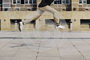 Young man jumping in front of university campus building