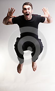 Young man jumping gray background