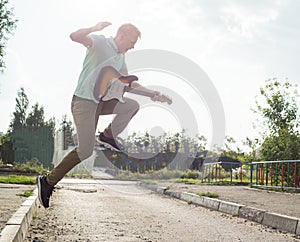 Young man jumping with a guitar on background of sky