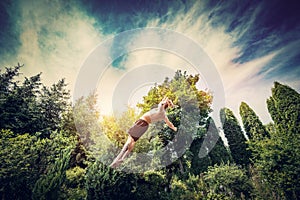 Young man jumping high in a garden.