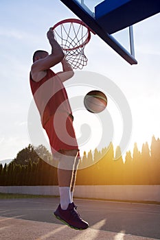 Young man jumping and making a fantastic slam dunk playing stree