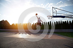 Young man jumping and making a fantastic slam dunk playing stree