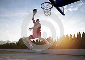 Young man jumping and making a fantastic slam dunk playing stree