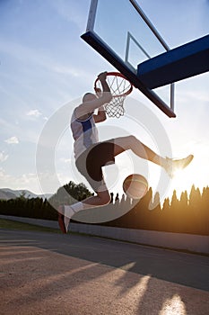 Young man jumping and making a fantastic slam dunk playing stree