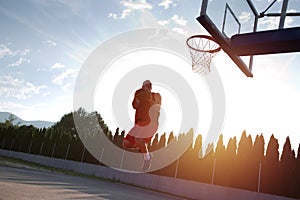 Young man jumping and making a fantastic slam dunk playing stree