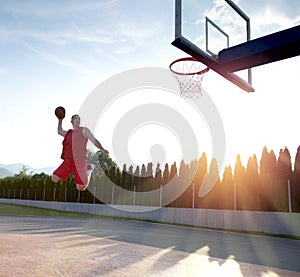 Young man jumping and making a fantastic slam dunk playing stree